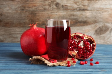 Photo of Glass of pomegranate juice and fresh fruits on table against wooden background