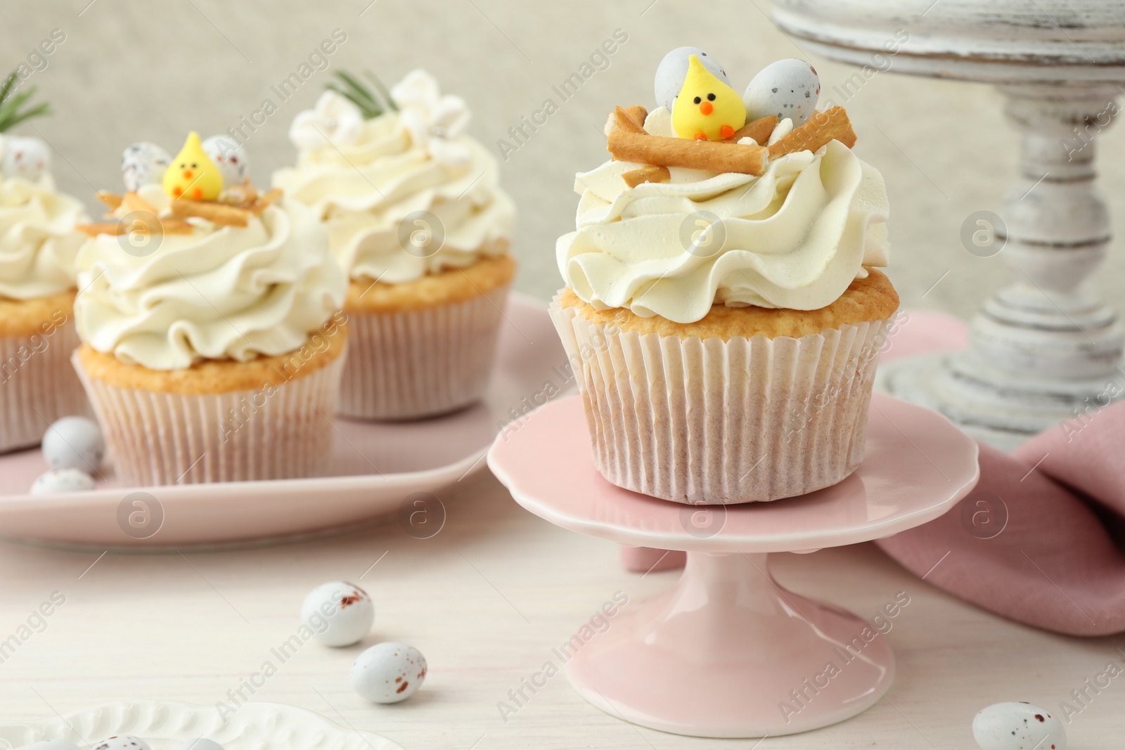 Photo of Tasty Easter cupcakes with vanilla cream on light wooden table