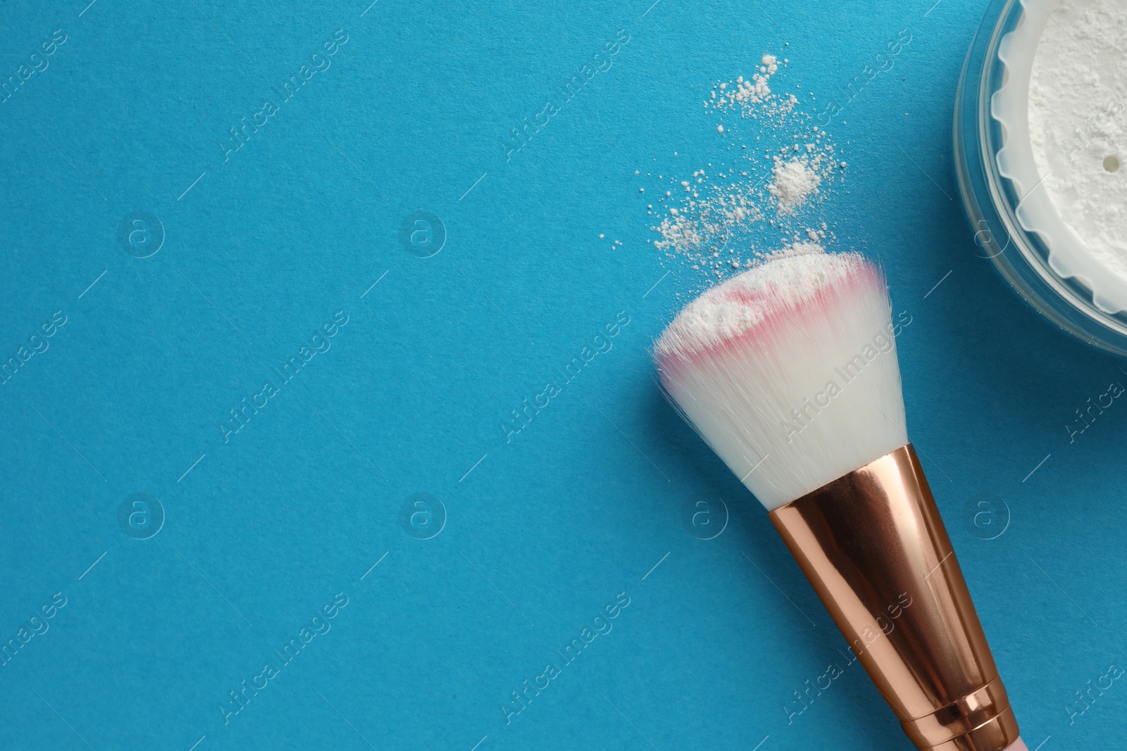 Photo of Rice loose face powder and makeup brush on light blue background, flat lay. Space for text