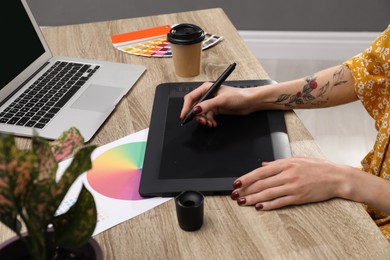 Photo of Professional designer with graphic tablet at wooden table, closeup