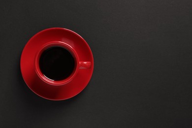 Photo of Red cup with aromatic coffee on black background, top view. Space for text