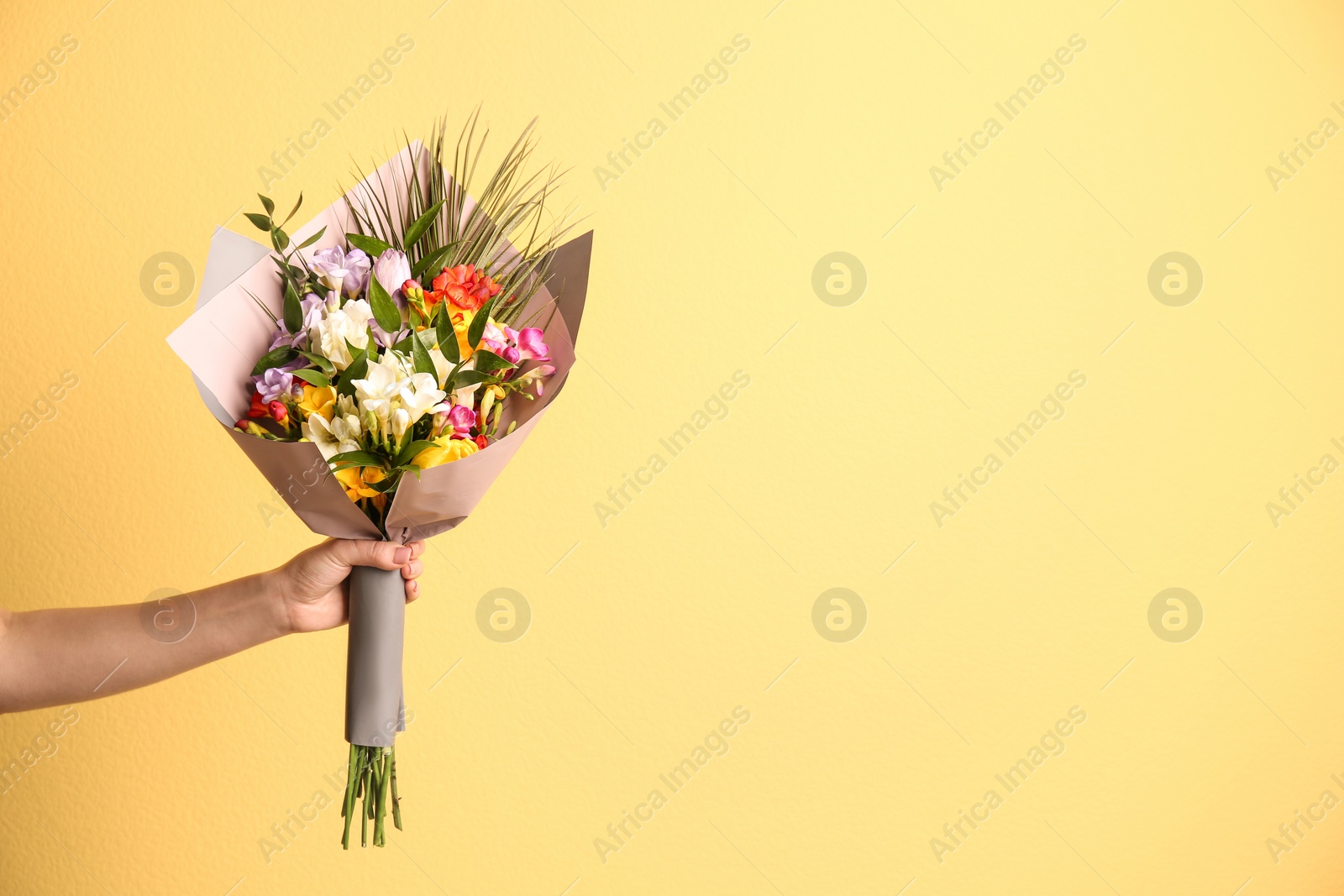 Woman with beautiful bouquet of freesia flowers on color background Photo of Woman with beautiful bouquet of freesia flowers on color background