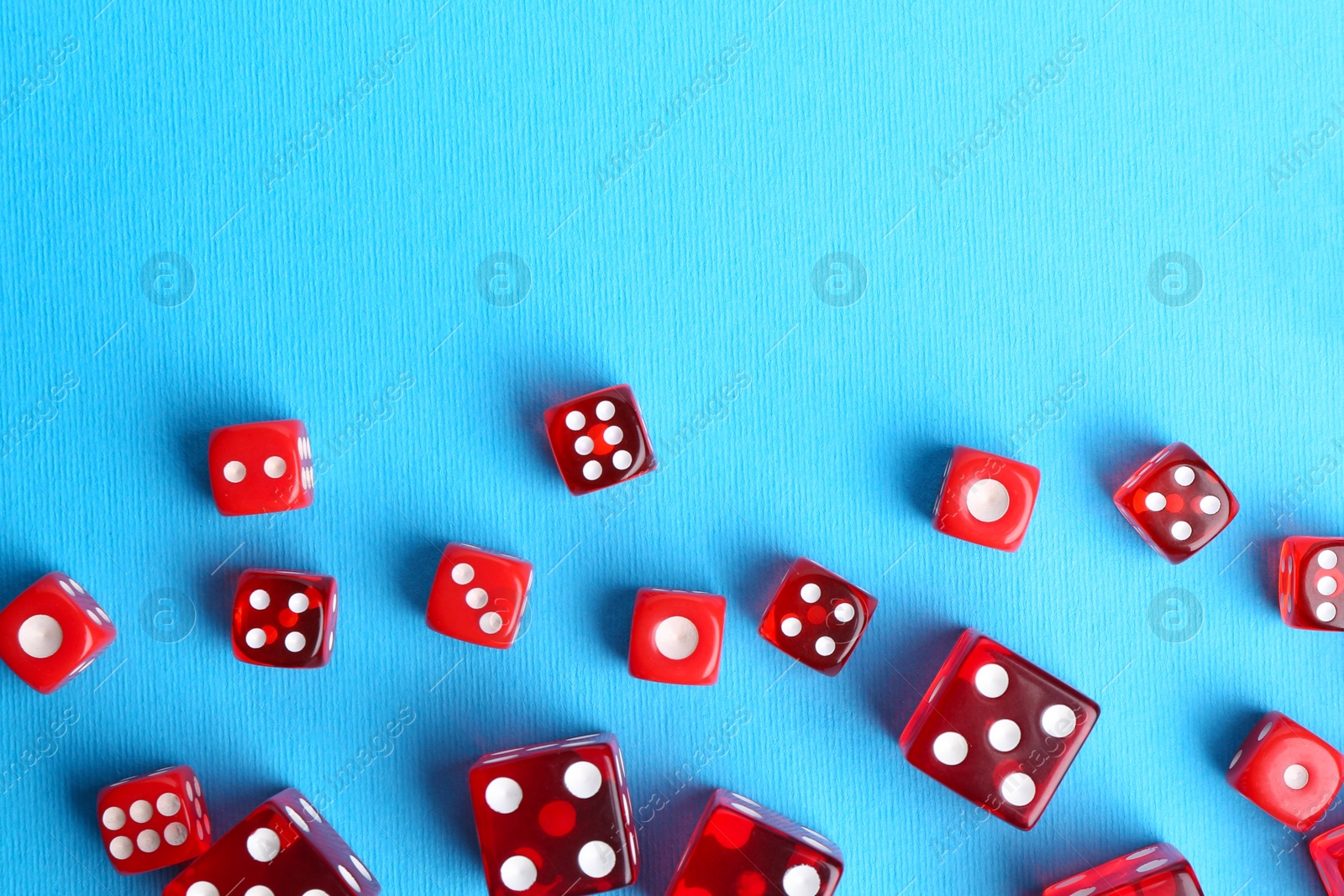 Photo of Many red game dices on light blue background, flat lay. Space for text