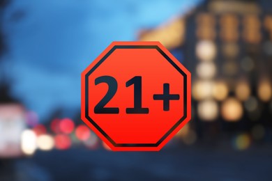 Image of Age limit sign 21+ years and blurred view of city at evening