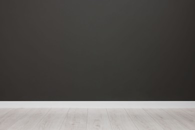 Photo of Empty room with black wall and wooden floor