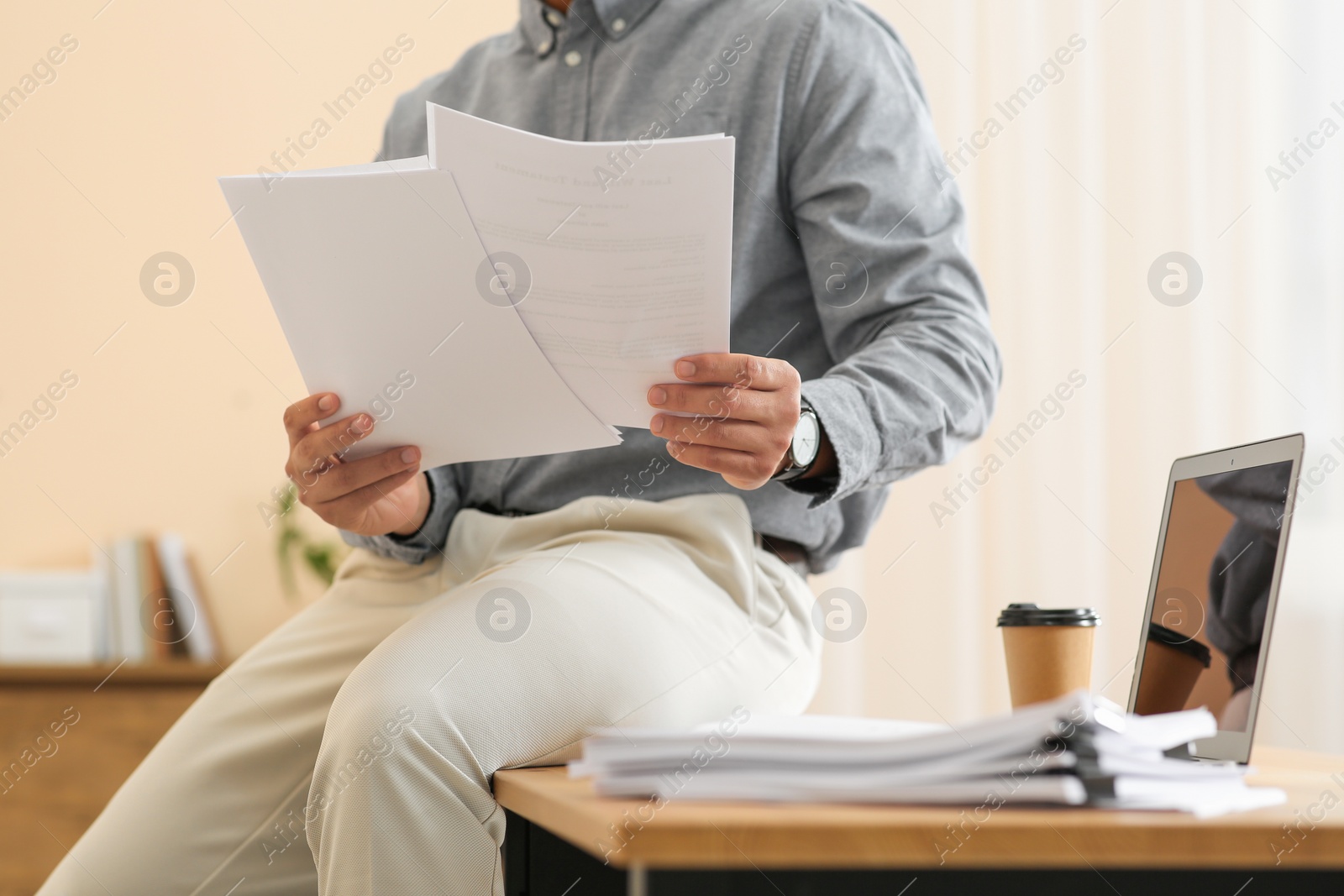 Photo of Man working with documents at wooden table in office, closeup