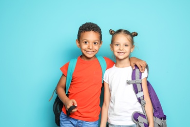 Photo of Little school children with backpacks on color background