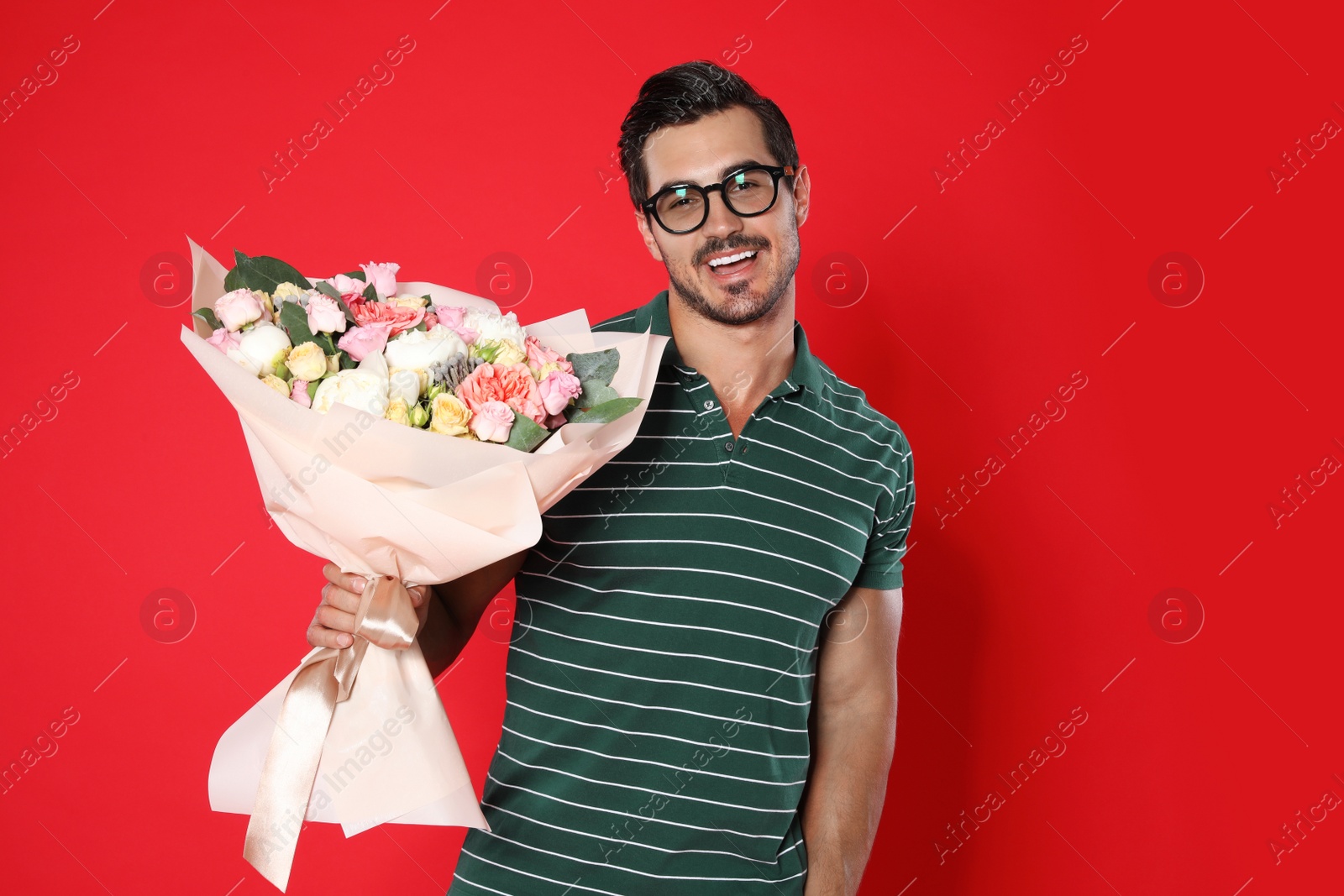 Photo of Young handsome man with beautiful flower bouquet on red background