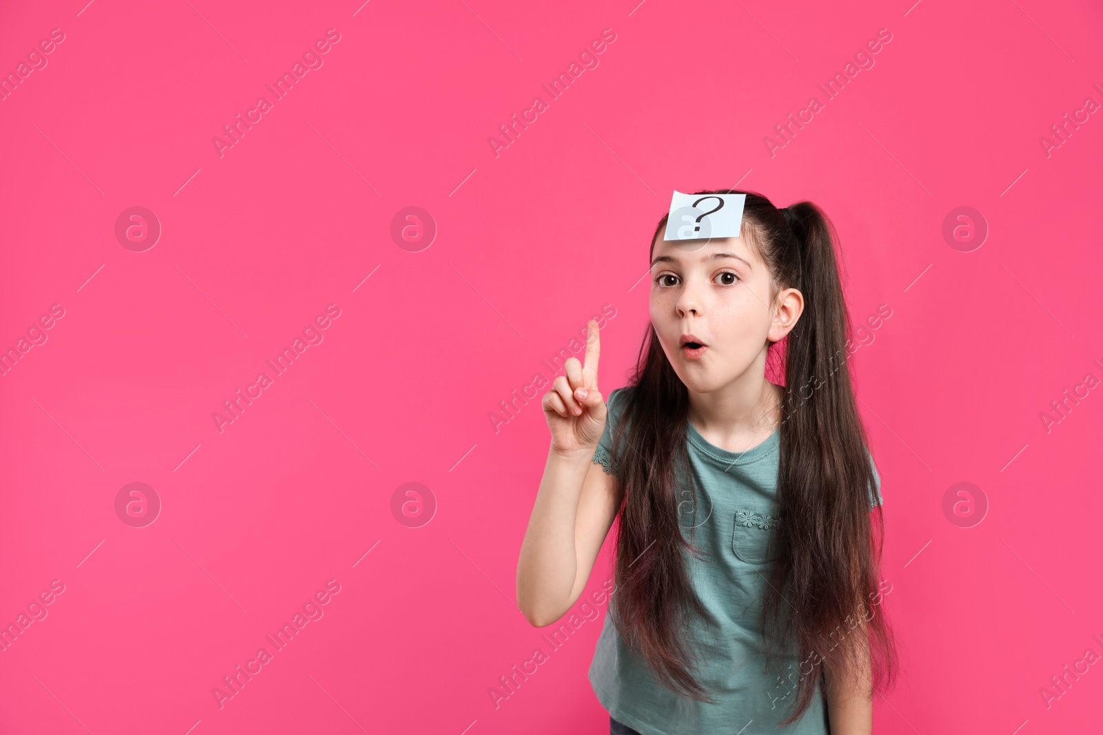 Photo of Emotional girl with question mark sticker on forehead against pink background. Space for text