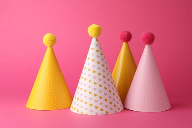 Beautiful party hats with pompoms on pink background