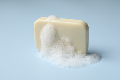 Photo of Soap and fluffy foam on light blue background