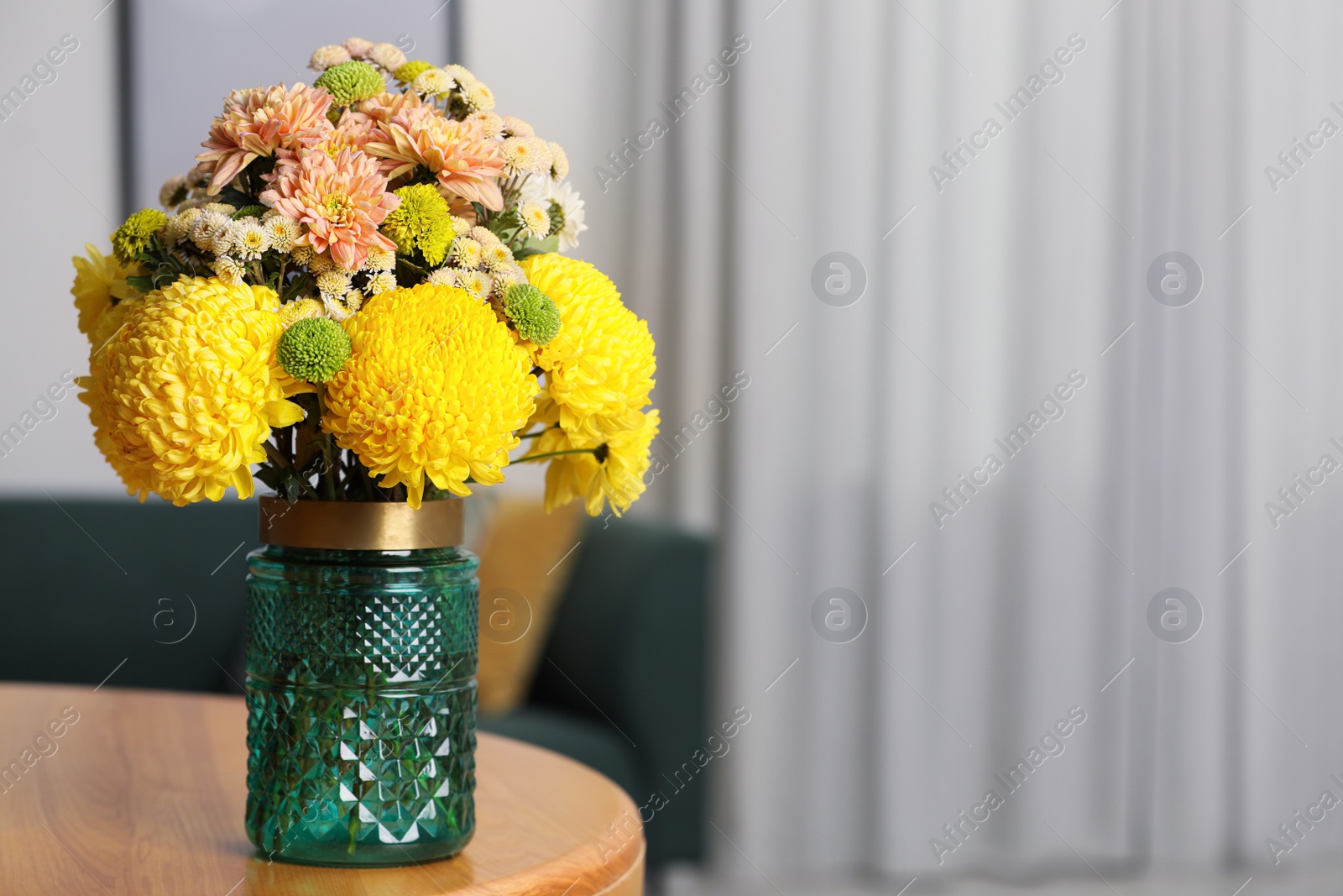 Photo of Bouquet of beautiful chrysanthemum flowers on wooden table indoors, space for text