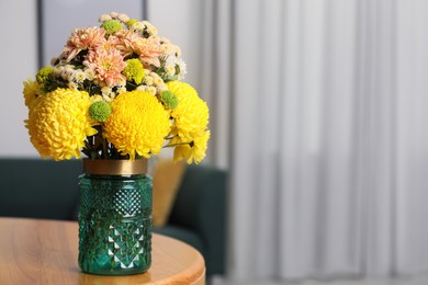 Photo of Bouquet of beautiful chrysanthemum flowers on wooden table indoors, space for text