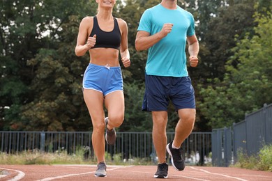 Photo of Healthy lifestyle. Sporty couple running at stadium, closeup