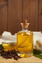 Essential oil and dried cloves on wooden table