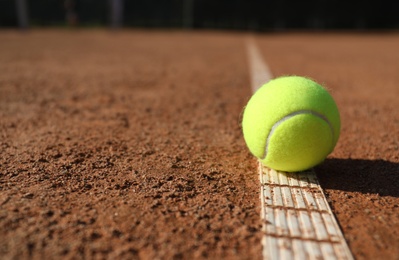 Bright yellow tennis ball on clay court