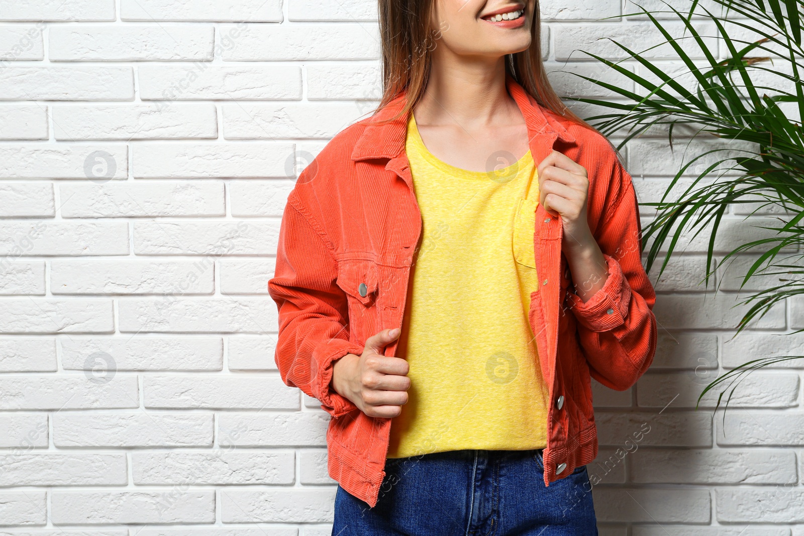 Photo of Young woman wearing blank t-shirt near white brick wall, closeup. Mockup for design