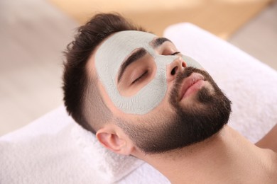 Man with mask on face lying in spa salon