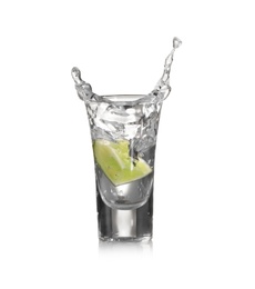 Photo of Lime slice falling into shot glass of vodka on beige background
