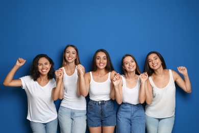 Photo of Happy women holding hands on blue background. Girl power concept