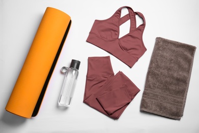 Photo of Yoga mat, stylish sportswear and bottle of water on white background, flat lay
