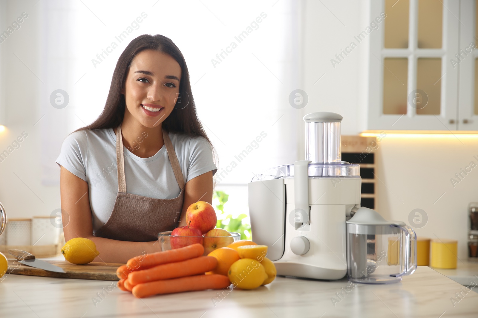 Photo of Young woman making tasty fresh juice at table in kitchen