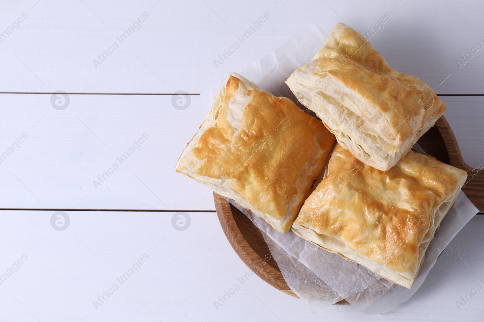 Photo of Delicious puff pastry on white wooden table, top view. Space for text