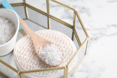Wooden spoon with sea salt for spa scrubbing procedure on white marble table