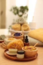 Dry flowers, loofah, soap bar, bottle of essential oil and jar with cream on wooden table indoors. Spa time