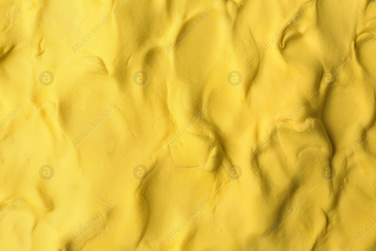 Photo of Yellow play dough as background, top view