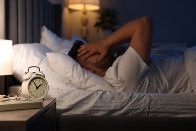 Photo of Man suffering from headache on bed, selective focus