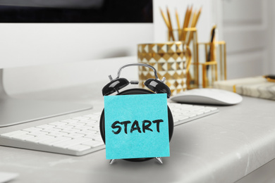 Image of New job. Sticker with word Start on alarm clock near computer in modern office