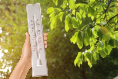 Image of Woman holding thermometer outdoors in spring, closeup