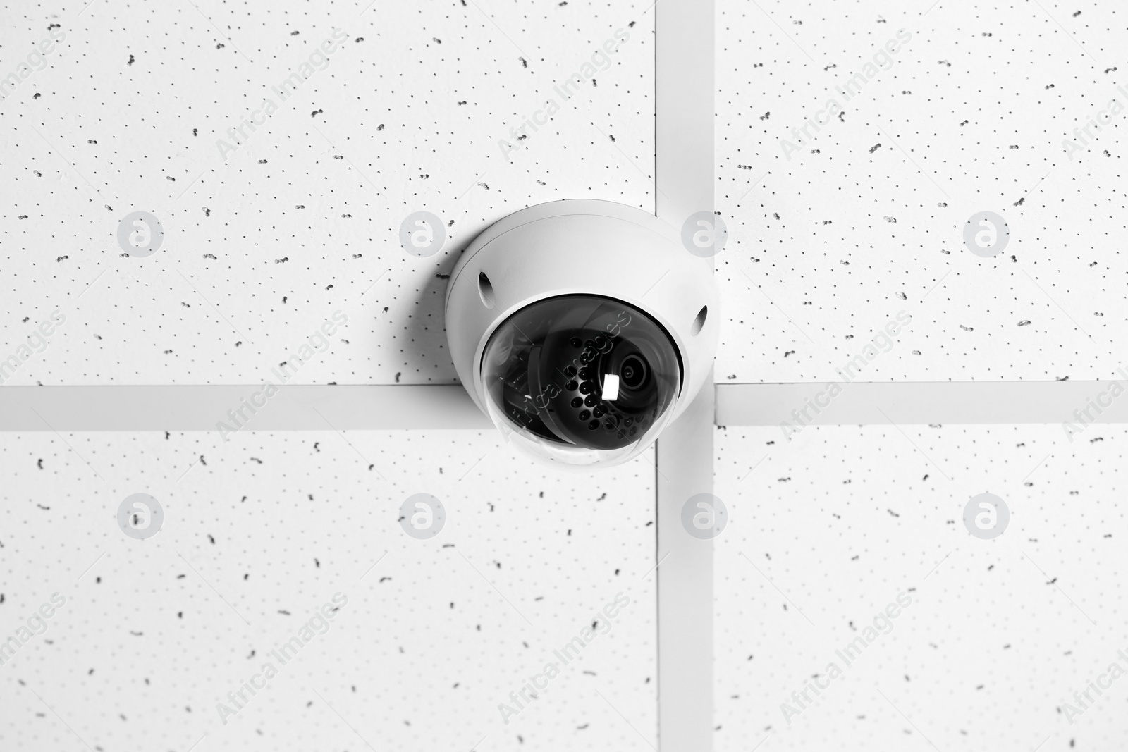 Photo of Modern security CCTV camera on ceiling indoors