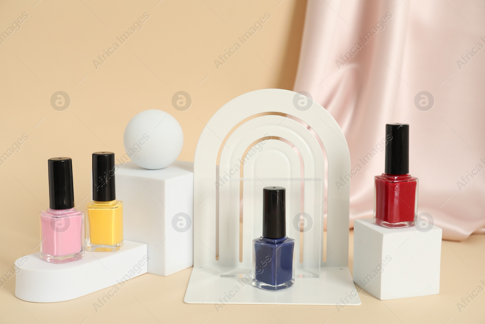 Photo of Stylish presentation of nail polishes on beige background