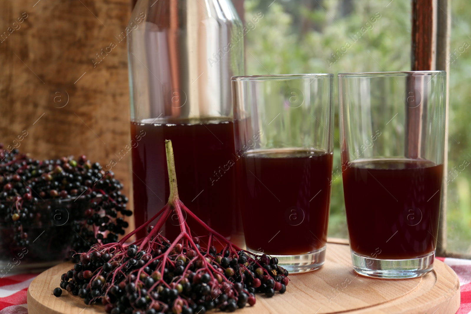 Photo of Elderberry drink and Sambucus berries on table near window