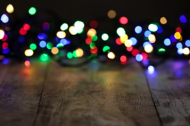 Photo of Colorful Christmas lights on wooden table, blurred view