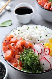 Photo of Delicious poke bowl with salmon and vegetables served on light grey table