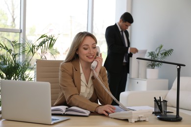 Photo of Secretary talking on phone at workplace in office