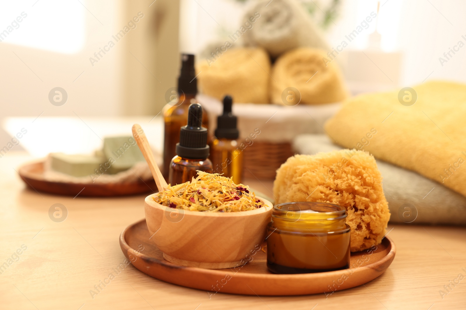 Photo of Dry flowers, loofah and jar with cream on wooden table indoors. Spa time