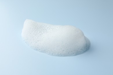 Drop of fluffy soap foam on light blue background