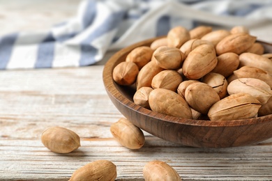 Photo of Pecan nuts in bowl on wooden table, space for text