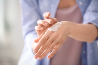 Photo of Young woman applying hand cream, closeup