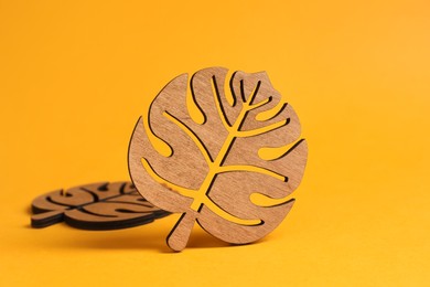 Leaf shaped wooden cup coasters on yellow background