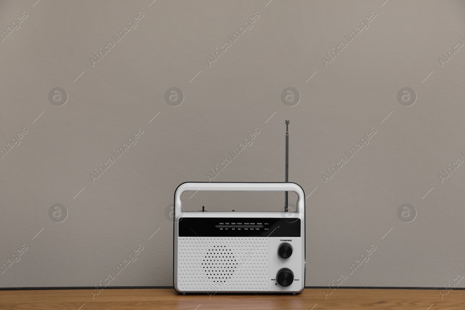 Photo of Retro radio receiver on wooden table against grey background