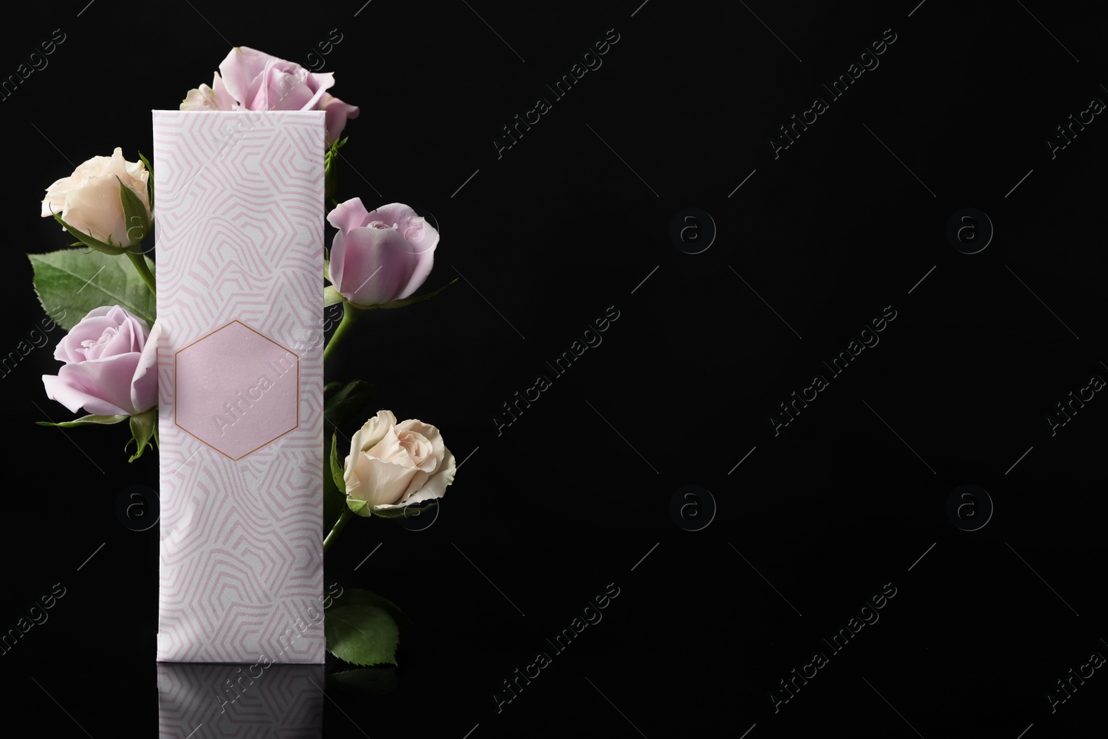 Photo of Scented sachet and roses on black background, space for text