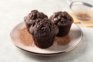 Photo of Delicious chocolate muffins and cacao powder on light grey table
