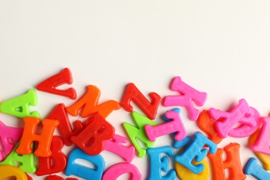 Photo of Many colorful magnetic letters on white background, flat lay. Space for text