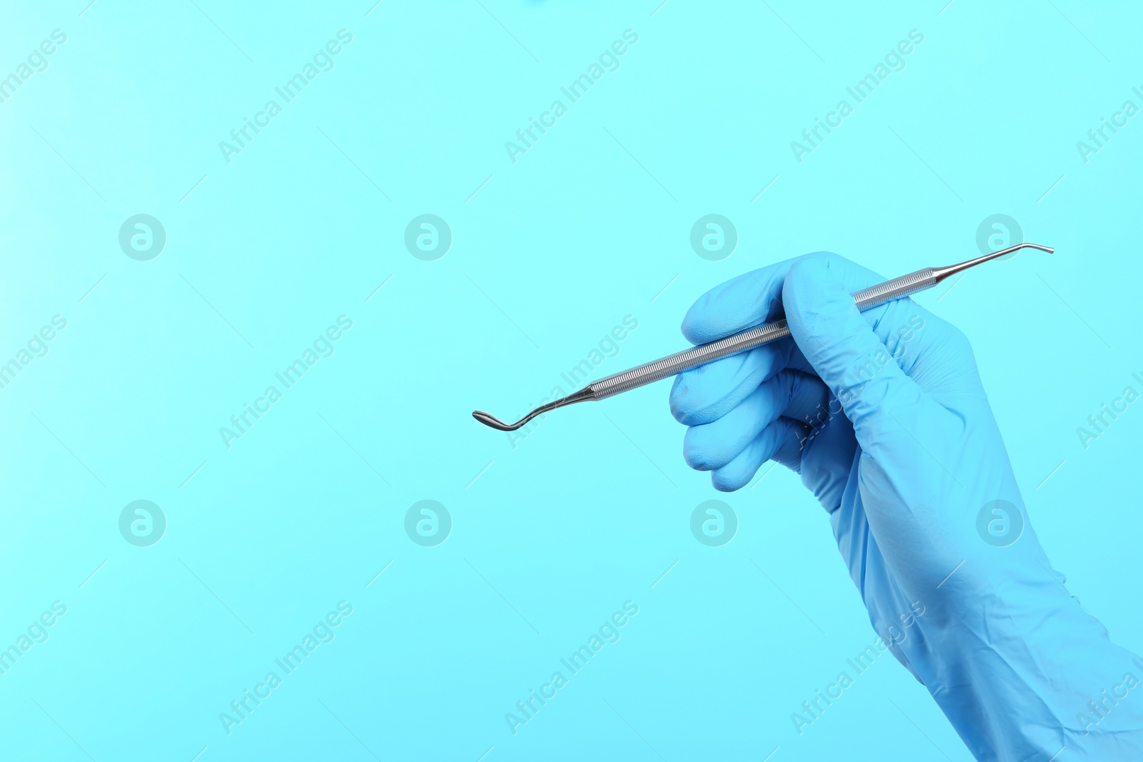 Photo of Dentist holding professional instrument on color background, space for text. Mouth and teeth care