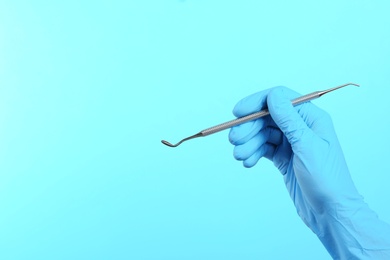 Photo of Dentist holding professional instrument on color background, space for text. Mouth and teeth care